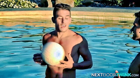 Two athletic twinks in swim trunks holding volleyball by pool
