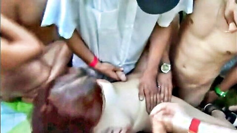 Group of Asian men in white coats touching redhead woman intimately