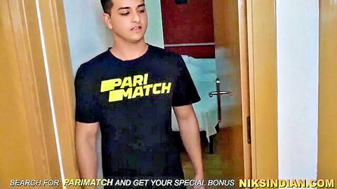 South Asian Indian guy in black Parimatch t-shirt standing in living room doorway
