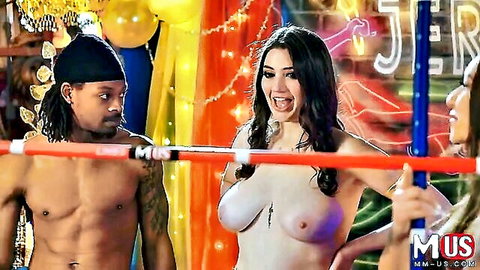Topless busty brunette with huge natural tits smiles excitedly in wrestling ring with muscular black men