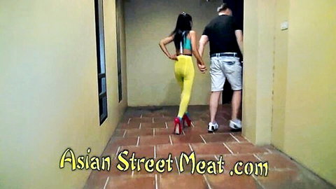 Sexy Asian teen in tiny yellow thong bikini and red heels struts hotel hallway with man