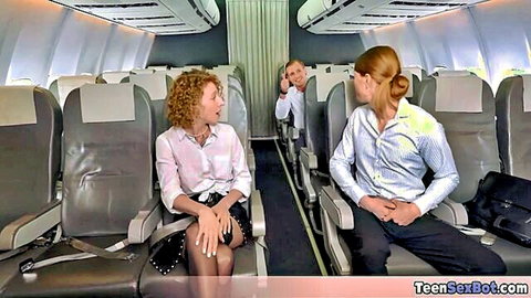 Two sexy redhead flight attendants in tight uniforms chatting seductively on airplane seats