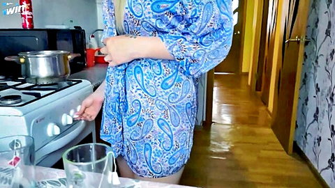 Blonde MILF in blue kimono robe bends over kitchen stove flashing bare ass cheeks