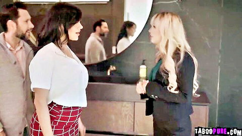 Brunette wife in red plaid skirt chats with busty blonde agent by bathroom sink as suited men watch in mirror