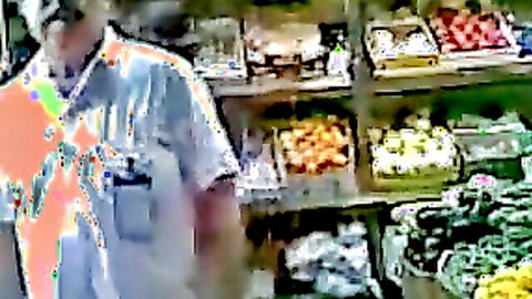 Dark-skinned shop owner in colorful shirt at fruit stand