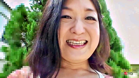 Smiling Asian woman with dark hair grins happily in outdoor selfie
