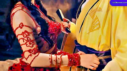 Seductive East Asian woman in skimpy red beaded lingerie holds dagger against man in yellow robe