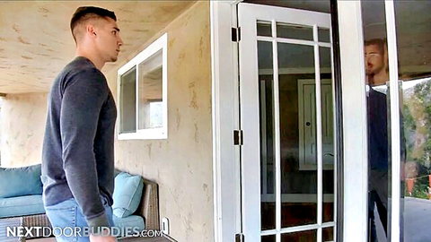 Muscular gay hunk in sweater stares at bearded stud through glass patio door