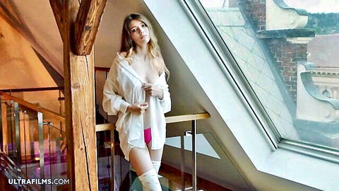 Skinny young babe with huge bare tits in open white shirt and pink panties posing topless by loft window
