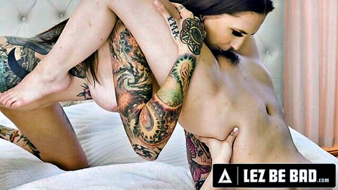 Tattooed brunette femdom pins skinny tattooed babe's legs back in piledriver, fingering wet pussy and sucking tits