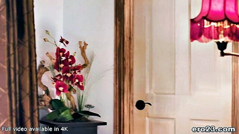 Cozy bedroom interior with red orchids, wooden door, and pink fringed lamp in elegant setting