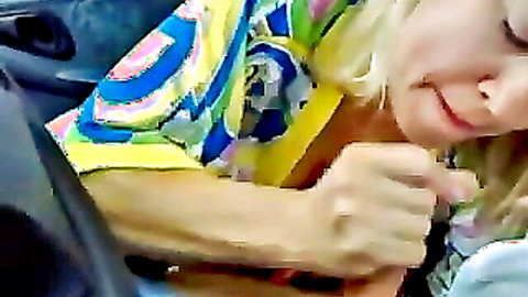 Blonde woman in colorful shirt giving quick car blowjob to man