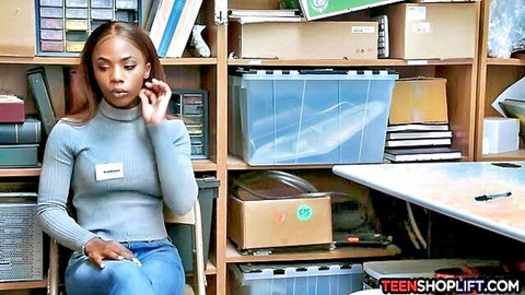 Ebony shop employee in grey sweater caught stealing, sitting in office on phone