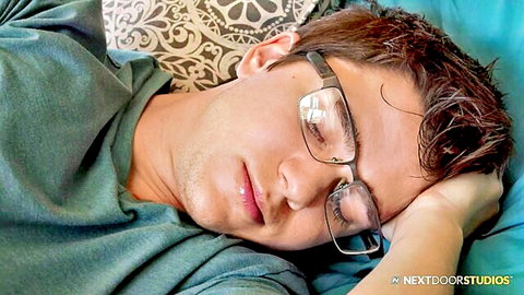 Handsome young man with glasses sleeping relaxed on bed in green shirt