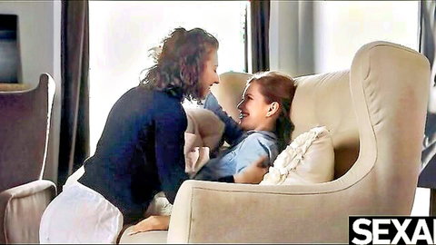 Busty lesbian beauties cuddling intimately on chair