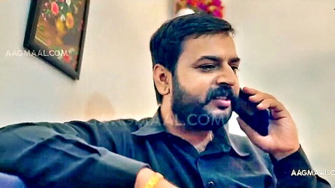 Bearded Indian man in black shirt talking intently on phone call