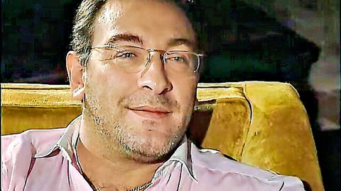 Mature bearded man in pink shirt smiling on couch, teasing vibe
