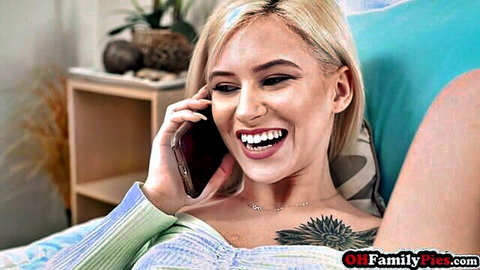 Blonde petite babe smiling wide on phone showing cleavage in green sweater