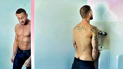 Tattooed muscular men in bathroom, shirtless hunk peeking through door, another at urinal