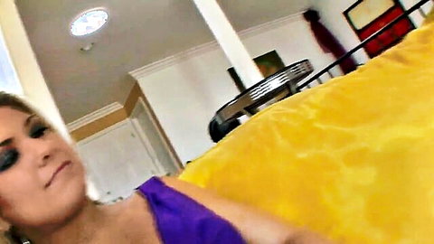 Blonde MILF in purple dress lounging seductively on bed