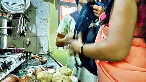 Desi step-sister-in-law in pink top and orange skirt flirting with brother-in-law in kitchen