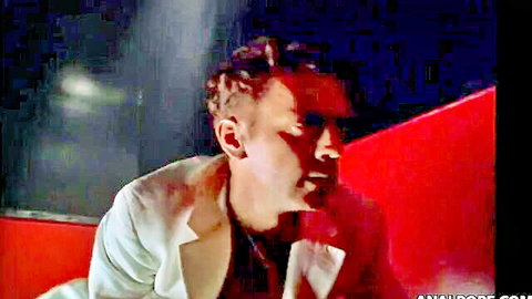 Intense retro man in open wet white shirt on red-lit stage in strip club scene