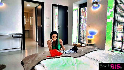 Simon Kitty kneeling in low-cut green top, showing cleavage on phone