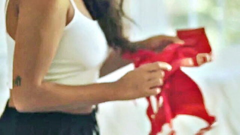 Seductive MILF in white tank top holding red lingerie, teasing viewer