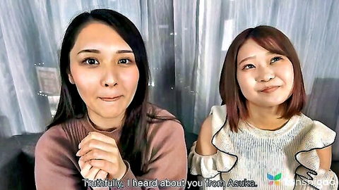 Two smiling Japanese women in sweaters chatting casually side by side