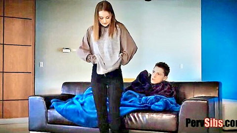 Danni Rivers redhead in sweater stands over blanket-covered guy on couch