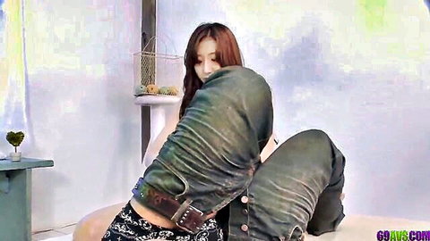 Asian woman in white top giving sensual thigh massage to partner's jeans in intimate couple session