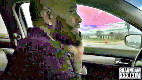 Bearded black man in purple shirt driving SUV at pink sunset with palm trees