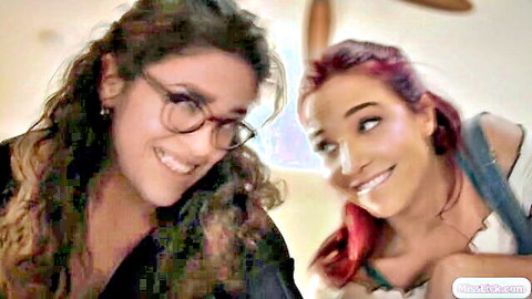 Smiling redhead MILF and brunette friend in intimate lesbian pose, glasses on brunette