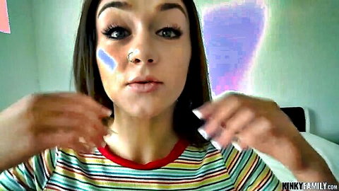 Young brunette teen with nose ring puckers lips seductively framing face in striped shirt