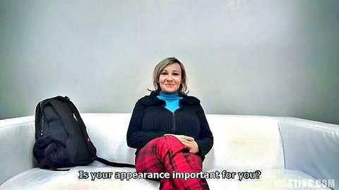 Alena in blue turtleneck, smiling on couch in amateur video preview