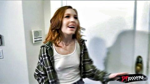 Petite redhead in plaid shirt smiles teasingly over tank top