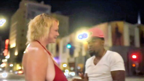 Curvy blonde MILF in red dress flirts with black stud outdoors at night