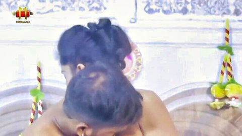 Two busty Indian babes nuzzling necks in traditional wedding decor with flowers and candles
