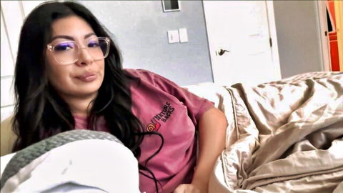 Sexy Latina therapist in glasses and family therapy shirt smiles seductively on bed