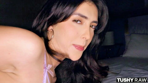 Jane Wilde in pink lingerie, seductive pose on bed, long dark hair