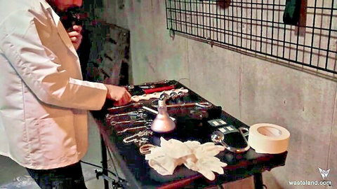 Gorgeous blonde in lab coat bound with wrist cuffs to BDSM table