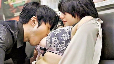 Asian couple in intimate embrace, man kissing woman's lace bra-covered breasts