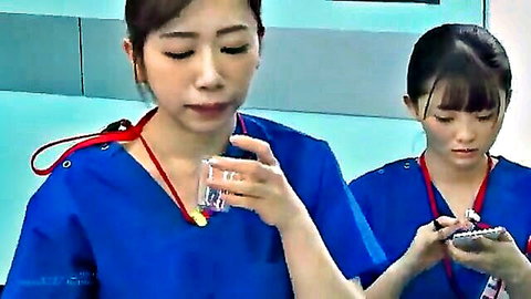 Two Asian nurses in blue uniforms examining yellow liquid in medical setting