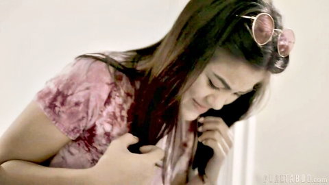 Young brunette Asian woman smiling playfully covering chest in pink tie-dye top with sunglasses on head