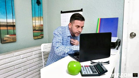 Handsome man in blue shirt working intently at laptop desk