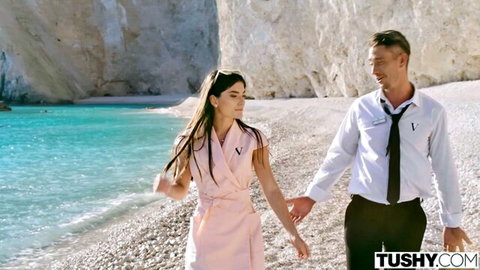 Stefany Kyler in pink dress holding hands with partner on sunny beach