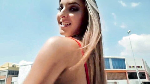 Amirah Adara blonde beauty smiling over shoulder in red top outdoors