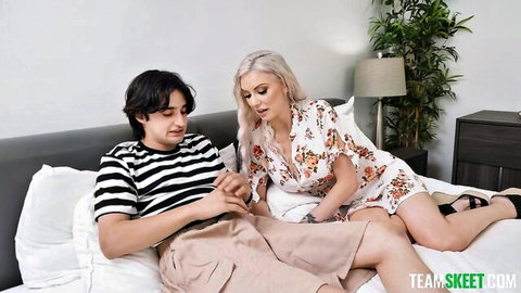 Blonde in floral dress teases young stepbrother on bed while he scrolls phone