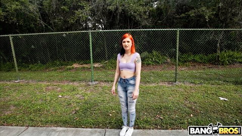 Sawyer Kelly posing outdoors in purple bra top and ripped jeans
