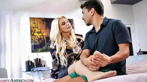 Tanned blonde MILF in dress gets sensual foot massage from handsome Latino stud on bed